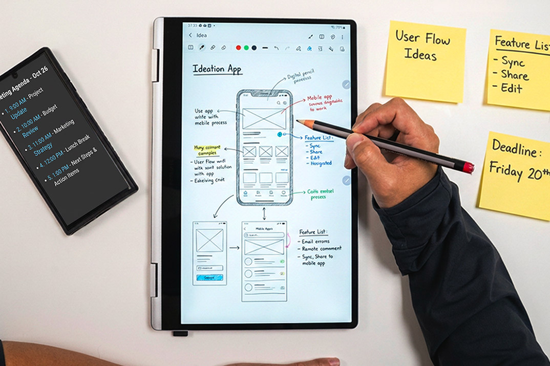 Two people sketching interface concepts together in a notebook with pen and pencil